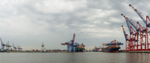 Cranes at commercial dock against sky