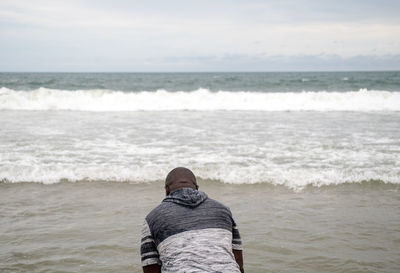 Rear view of man on beach against sky