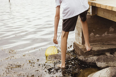 Low section of boy catching fish at sea