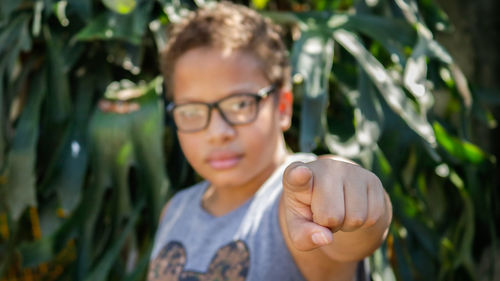 Portrait of boy pointing against plants