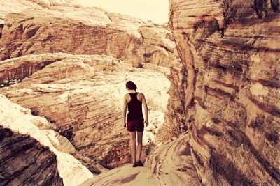 Rear view of teenage girl standing looking down over mountain