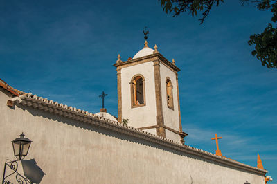 Overview of lamp, wall and old belfry under blue sunny sky in paraty, brazil