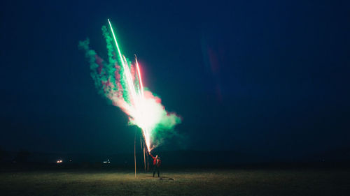 Man holding firework at night against sky