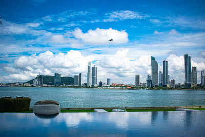 River by modern buildings in city against sky