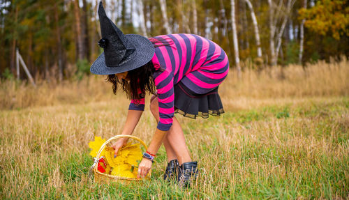 Witch with pumpkin in the autumn forest. halloween party concept