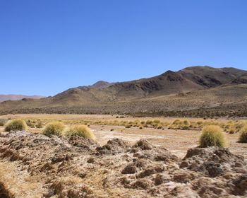 Scenic view of arid landscape against clear blue sky