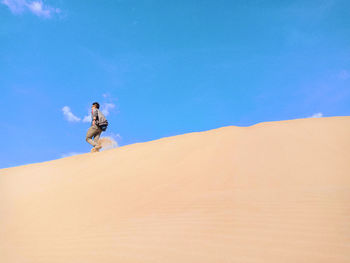 Man walking in desert against blue sky