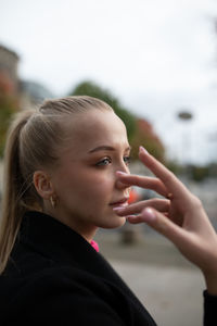 Close-up young woman gesturing while standing outdoors