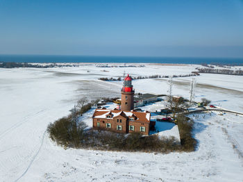 Traditional building by sea against sky during winter