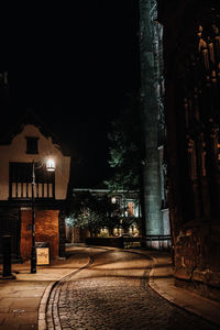 Illuminated street amidst buildings at night