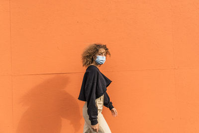 Woman standing against orange wall