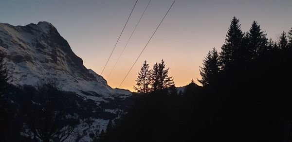 Silhouette trees and mountains against sky during sunset