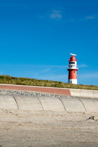 Lighthouse by building against sky