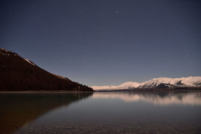 Scenic view of lake and mountains against sky at night