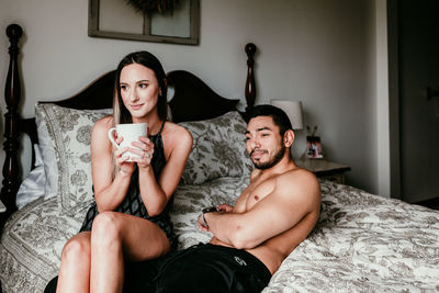 Young woman and man sitting on bed at home
