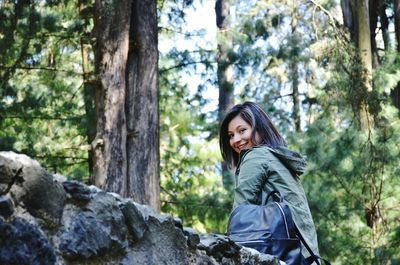 Portrait of happy woman against trees at forest