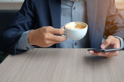 Midsection of man holding coffee cup