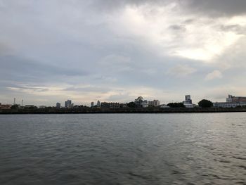 Sea by buildings against sky in city