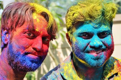 Close-up portrait of smiling men with colored powder on face