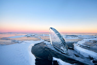 Frozen sea against sky during sunset