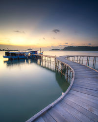 Pier over sea against sky during sunset