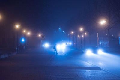 Silhouette person walking on illuminated street during winter at night