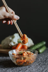 Cropped hand holding food with chopsticks on table