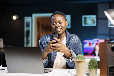 Young man using mobile phone while sitting on table