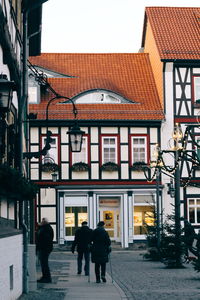 Rear view of people walking on street amidst buildings in city