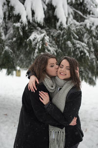 Close-up of young women embracing while standing on snow during winter