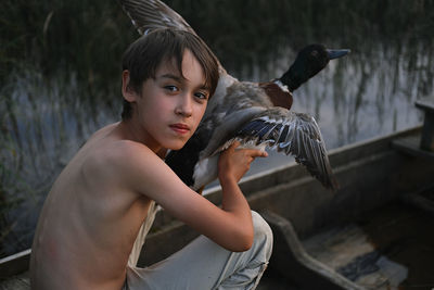 Portrait of boy holding bird in boat