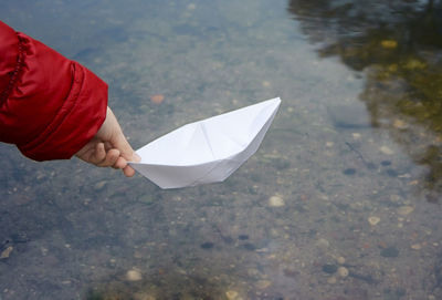 Close-up of woman holding paper boat over water