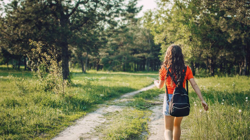 Rear view of woman walking on grassy field