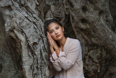 Portrait of a beautiful young woman with tree trunk