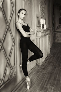 Cute charming young ballerina in a warm-up bodysuit posing in a loft