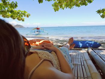 Woman relaxing on beach against sky