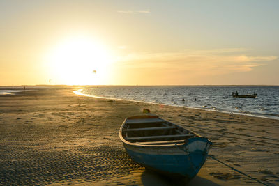 Boat moored at seashore during sunset