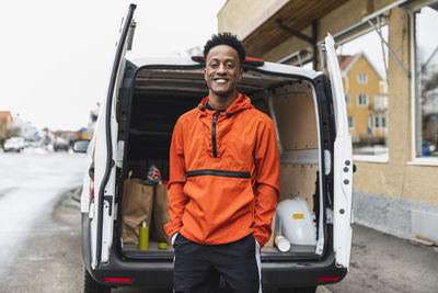 Portrait of young man standing against bus