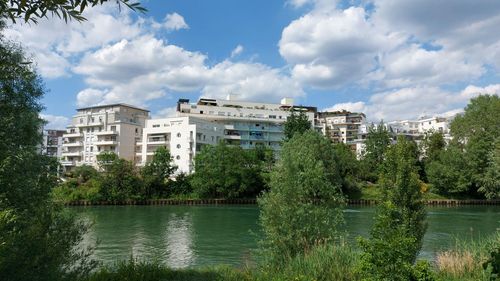 Buildings by lake against sky