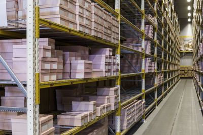 Packages on racks by narrow empty aisle at distribution warehouse