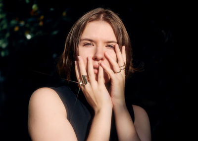 Portrait of young woman against black background