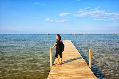 Full length of woman standing on pier over sea against sky