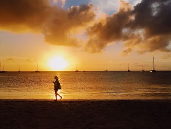 Silhouette man standing on beach against sky during sunset