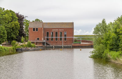 House by lake against sky