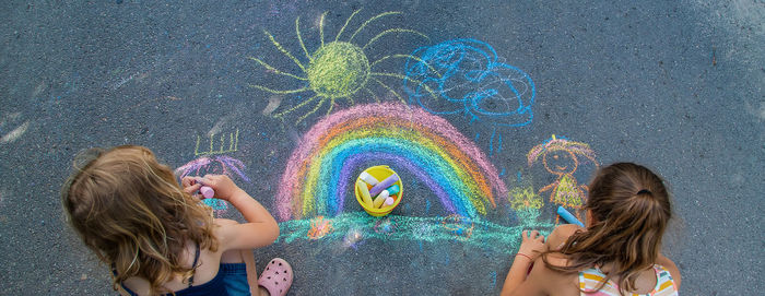 Girls drawing with chalk on sidewalk