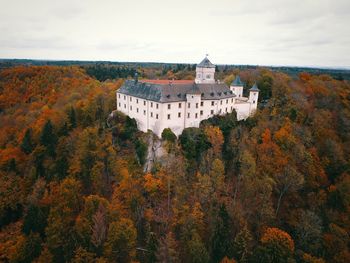 Buildings by trees against sky during autumn