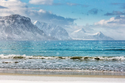 Scenic view of sea and snowcapped mountains against sky