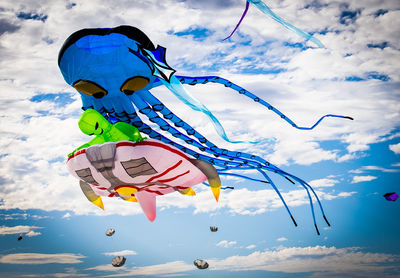 Low angle view of kites flying against sky