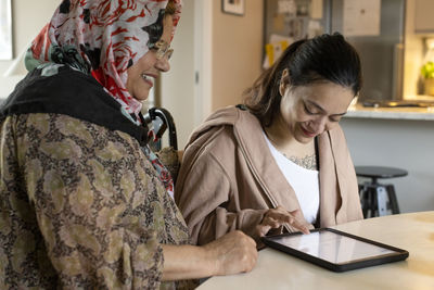 Woman with disability using tablet pc by mother at home