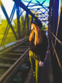 Woman standing on railway bridge in sunny day